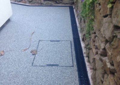 A resin bound recess cover set into a pathway, along with a bordering aco drain