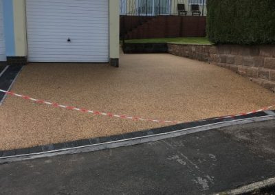 Freshly laid resin separated from the public walkway by a dark block paving border